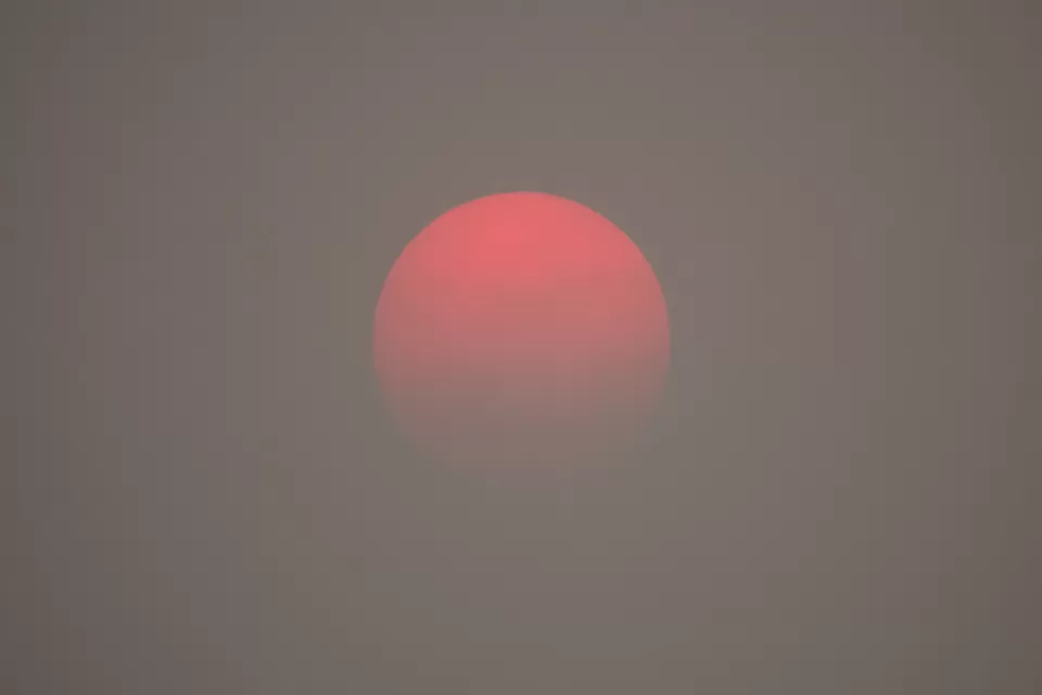 A red sun appears on the horizon, as obscured by haze from wildfire smoke.